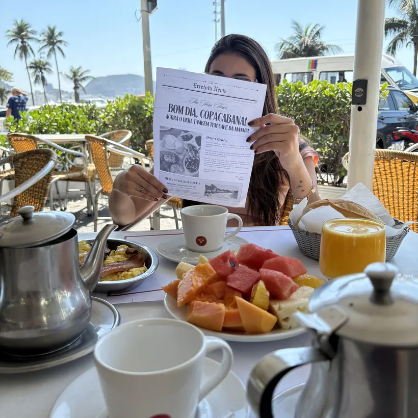 Café da manhã do Hera servido na calçada, com bule, frutas e suco